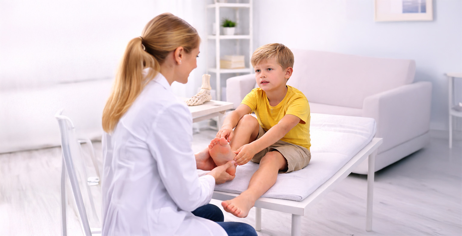 Podotherapeut onderzoekt de voet van een kind tijdens een consult in de praktijk